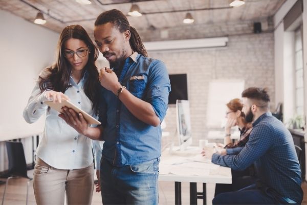 6 tips on how to prevent a security breach co-workers looking at tablet and co-workers working on computer in the background